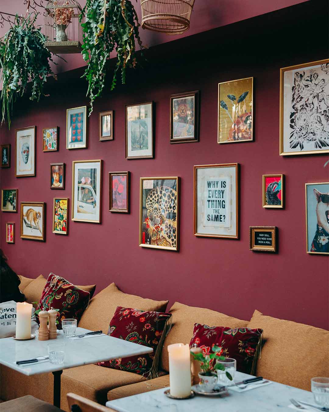 Muur met tientallen lijsten met prints bij Paco Ciao