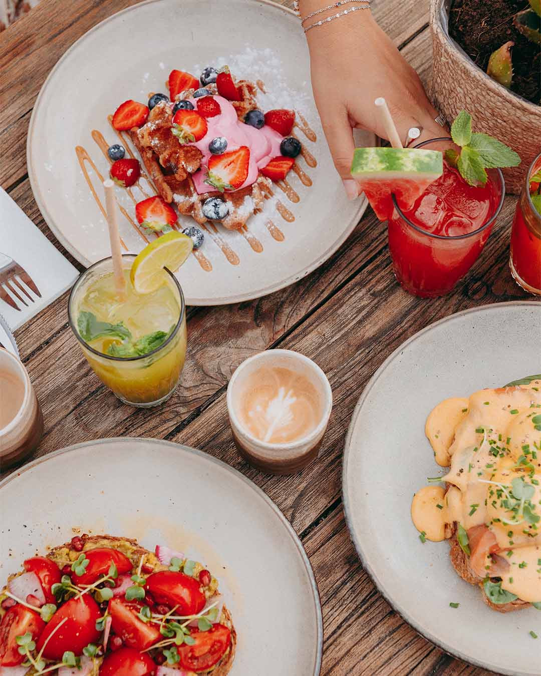Bovenaanzicht ontbijt met verse sapjes en wafel met rood fruit en eggs benedict